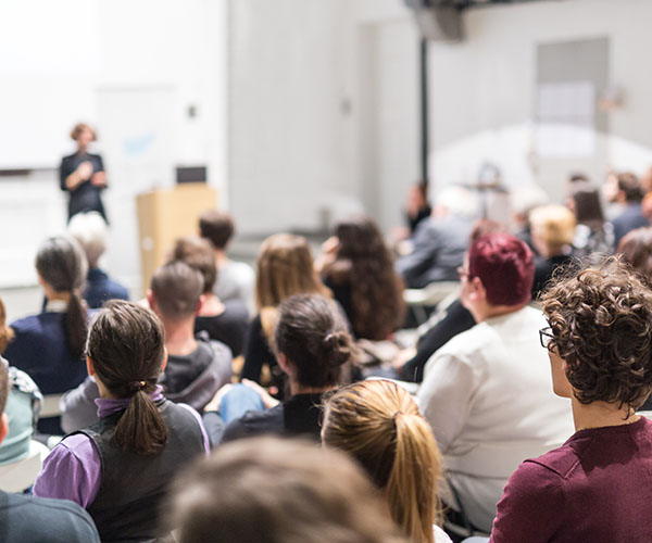 A lecture hall in a higher education venue with students watching the teacher who stand at the front.